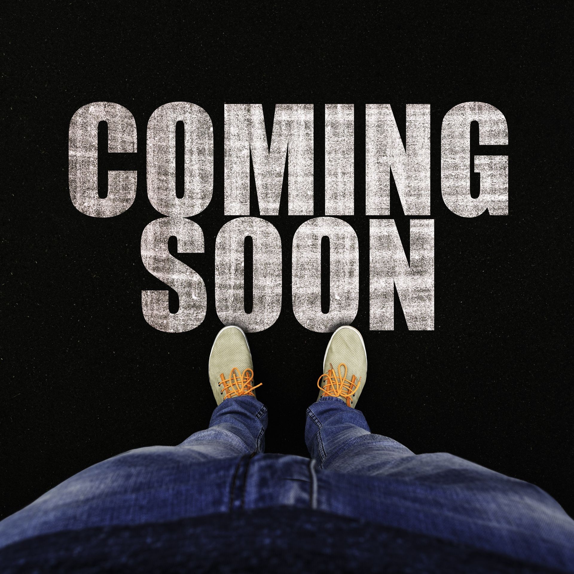 Top view on legs in sports sneakers and jeans on asphalt with text coming soon